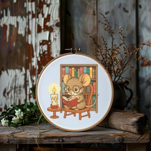 May include: Cross-stitch embroidery in a wooden hoop. The design features a cartoon mouse wearing glasses and reading a book in front of a bookshelf. A lit candle sits on a small table. The background is a rustic wooden wall.