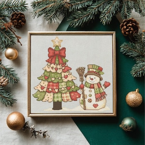 Puede incluir: Un bordado enmarcado con un árbol de Navidad y un muñeco de nieve. El árbol tiene un lazo y una estrella rojos, con secciones verdes y rojas estilo patchwork. El muñeco de nieve lleva un sombrero, una bufanda y sostiene una escoba. Decoración festiva navideña.