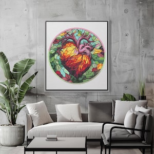 Puede incluir: Una pintura colorida de estilo vitral que representa un corazón humano rodeado de hojas verdes. El corazón es rojo, naranja y amarillo con un diseño anatómico detallado. La pintura está enmarcada y colgada en una pared gris.