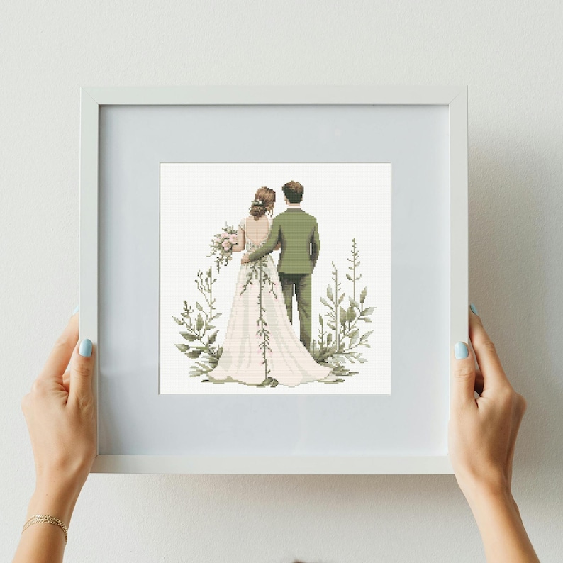 May include: A framed illustration of a bride and groom in a minimalist style. The couple is standing back to back, with the bride in a white gown and the groom in a green suit. They are surrounded by green foliage.