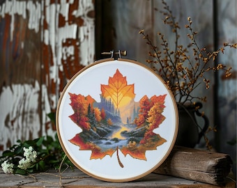 May include: A cross-stitch embroidery in a wooden hoop, featuring a maple leaf design. The leaf is filled with a landscape of autumn trees, a river, and a sunset. The colors include shades of orange, yellow, green, and blue.