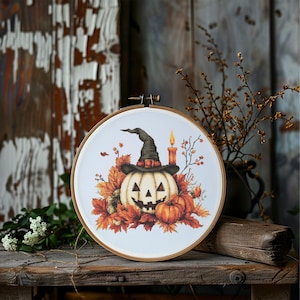 May include: A white pumpkin with a witch's hat and a lit candle, surrounded by orange and brown autumn leaves.