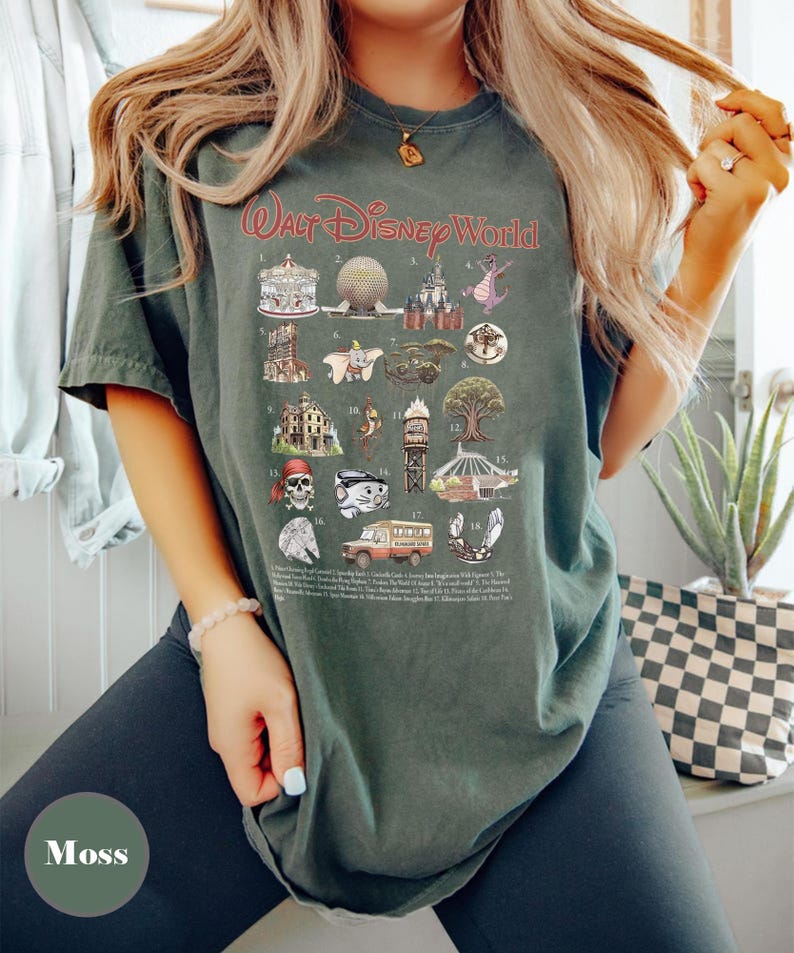 May include: Moss green t-shirt featuring a graphic of Walt Disney World icons. The shirt displays illustrations of various attractions and characters, with the text "Walt Disney World" in red script. A fun and colourful design.