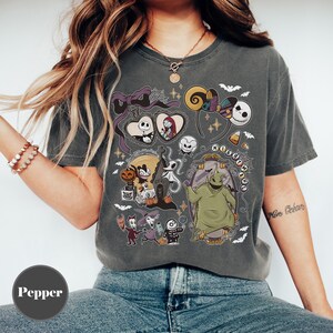 Op de afbeelding: Donkergrijs T-shirt met een collage van personages en elementen uit "The Nightmare Before Christmas". Het ontwerp bevat Jack Skellington, Sally, Zero, Oogie Boogie en andere iconische beelden. Het shirt heeft een vintage, licht vervaagde uitstraling.