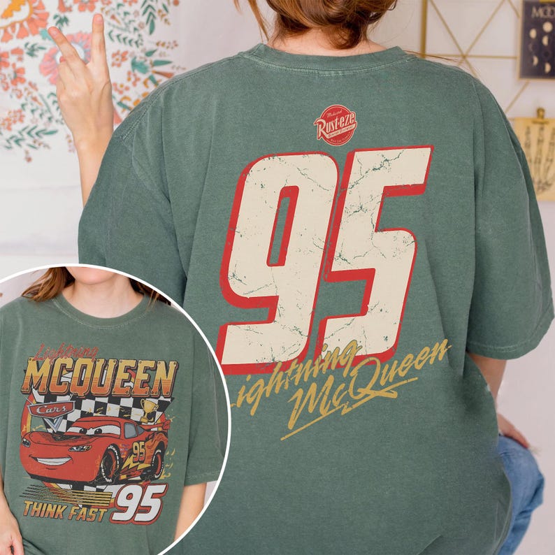 May include: Green t-shirt featuring a large number "95" in red and white on the back, with "Lightning McQueen" in gold script. The front of the shirt displays a graphic of the character Lightning McQueen from the movie Cars.