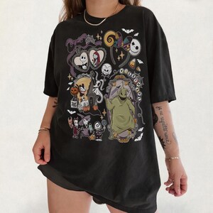 Op de afbeelding: Zwart T-shirt met een kleurrijk grafisch ontwerp met personages uit "The Nightmare Before Christmas". Het ontwerp bevat Jack Skellington, Sally, Oogie Boogie en andere elementen uit de film. Het shirt heeft een relaxte pasvorm.
