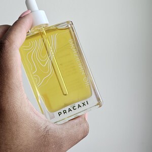 May include: A clear rectangular bottle of Brazilian Pracaxi oil with a white dropper. The bottle contains a yellow liquid and has white text that reads "BRAZILIAN OIL" and "PRACAXI".