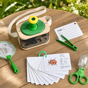 Puede incluir: Una caja de observación de insectos de madera con tapa verde, ocular amarillo y correa blanca. El set incluye una pequeña red verde, pinzas de plástico verde, una tarjeta de observación y un anillo de tarjetas con una ilustración de mariquita.