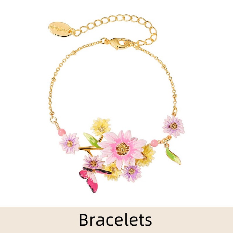 May include: A gold chain bracelet with a floral design featuring pink, yellow, and purple flowers and a pink butterfly charm. The bracelet is part of a collection of bracelets.