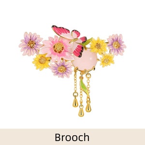 May include: A gold-toned brooch featuring a cluster of pink, yellow, and purple enamel flowers with a pink butterfly and a pink stone pendant with a chain and dangling drops.