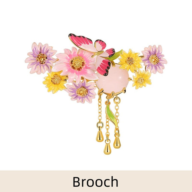 May include: A gold-toned brooch featuring a cluster of pink, yellow, and purple enamel flowers with a pink butterfly and a pink stone pendant with a chain and dangling drops.