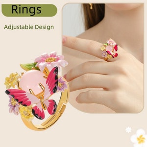 May include: Adjustable ring featuring a pink butterfly with red wings, surrounded by pink, yellow, and purple flowers. The ring has a pink stone in the center.
