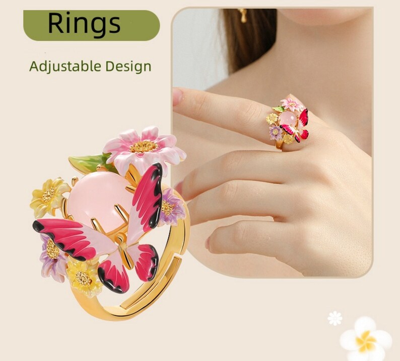 May include: Adjustable ring featuring a pink butterfly with red wings, surrounded by pink, yellow, and purple flowers. The ring has a pink stone in the center.