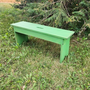 May include: A green wooden bench with a simple design. The bench is made of solid wood and has a natural finish. It is perfect for adding a touch of rustic charm to any outdoor space.