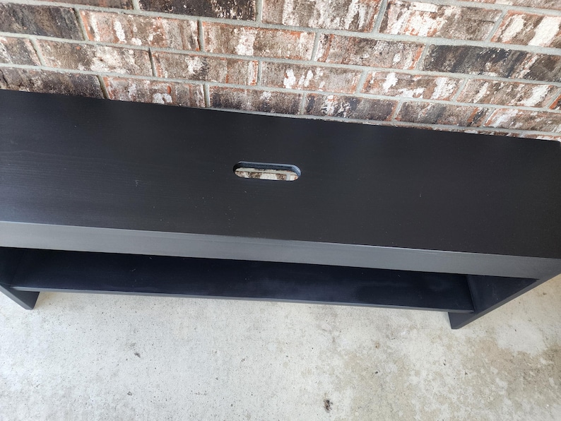 May include: Black wooden bench with a single shelf and a rectangular cutout in the top surface.