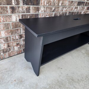 May include: A black wooden bench with a shelf underneath. The bench has a simple design and is made of solid wood.