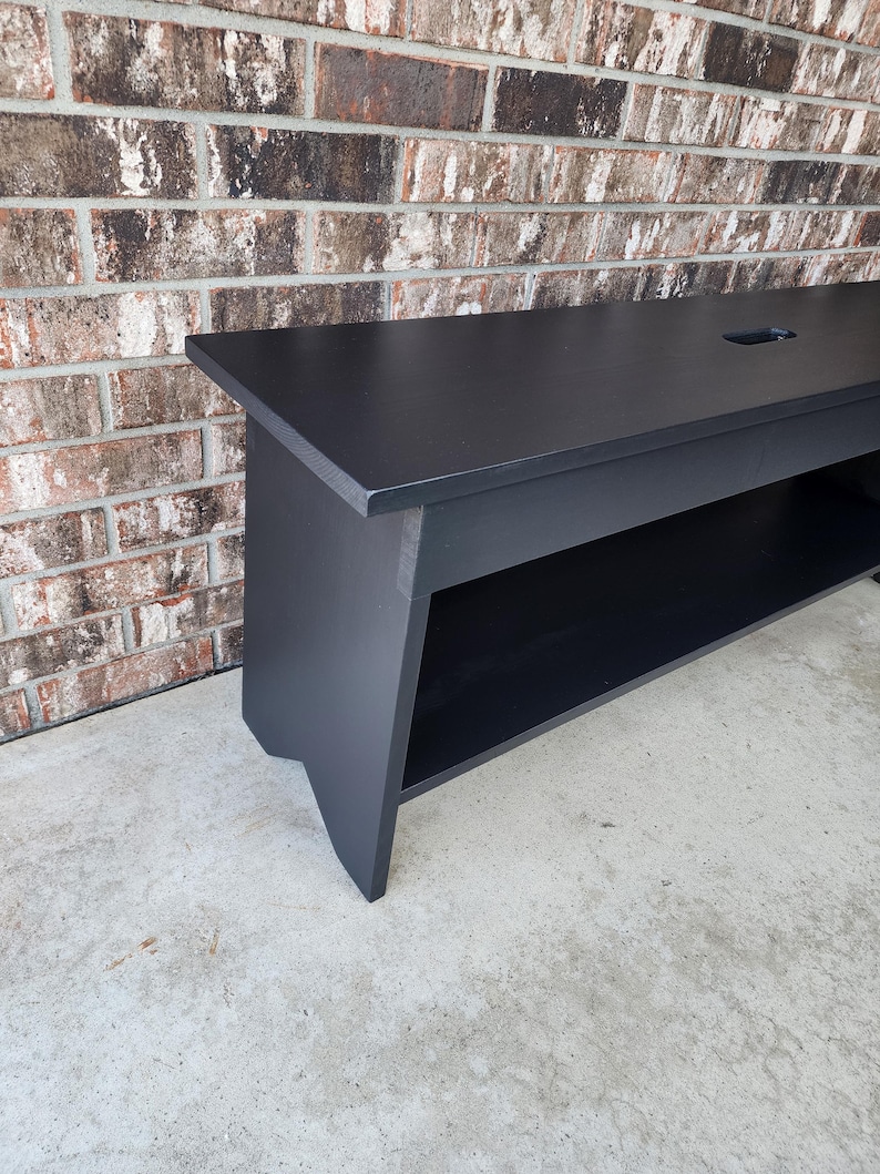 May include: A black wooden bench with a shelf underneath. The bench has a simple design and is made of solid wood.