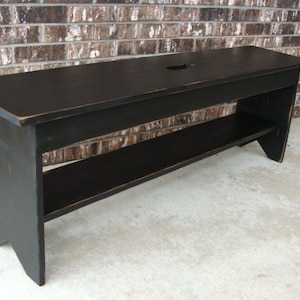 May include: Black wooden bench with a shelf and a cutout in the top. The bench has a distressed finish.