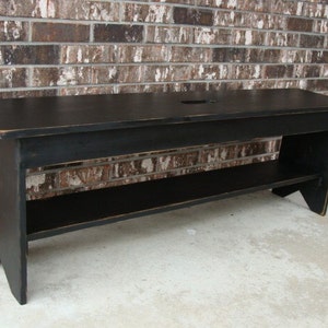 May include: A black wooden bench with a shelf underneath. The bench has a distressed finish and a simple design.