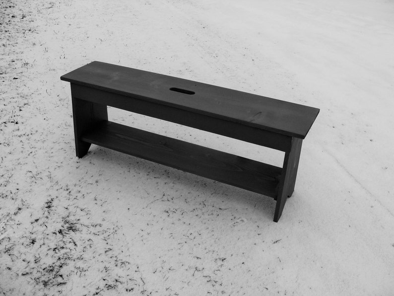 Pu&ograve; includere: Una panca di legno nera con uno scaffale sotto. La panca &egrave; su una superficie bianca.