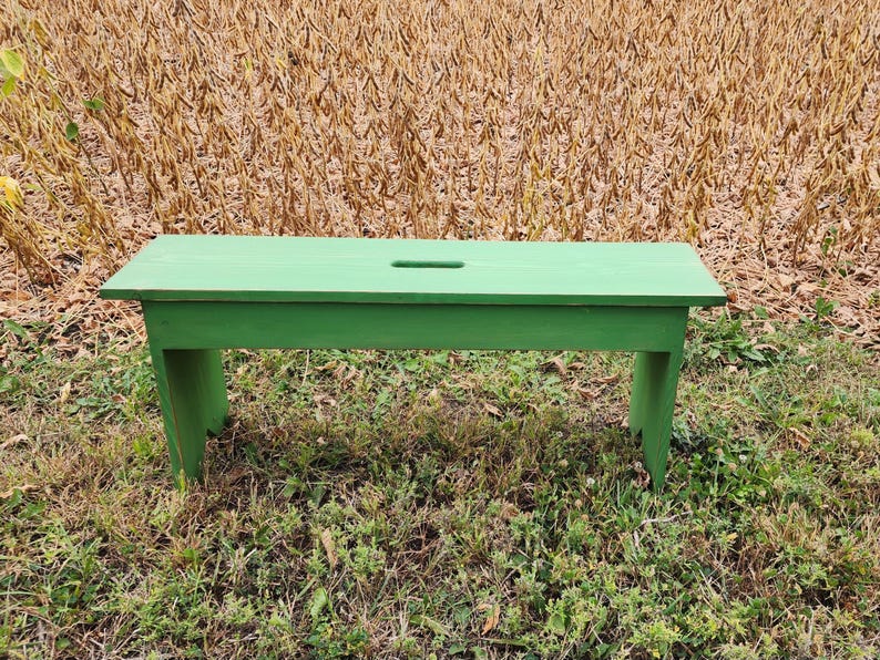 May include: A green wooden bench with a simple design. The bench is made of solid wood and has a smooth finish. It is perfect for adding a touch of rustic charm to any outdoor space.