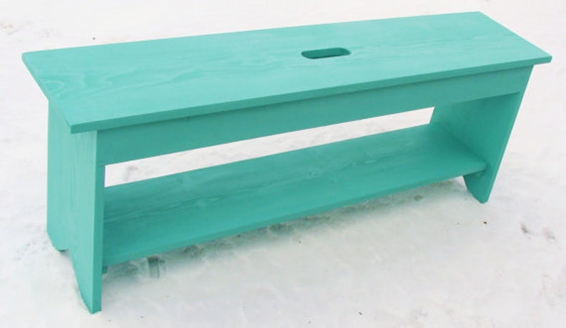 Pu&ograve; includere: Una panca in legno blu turchese con uno scaffale e un ritaglio nella parte superiore. La panca &egrave; realizzata in legno massello e ha un aspetto rustico.