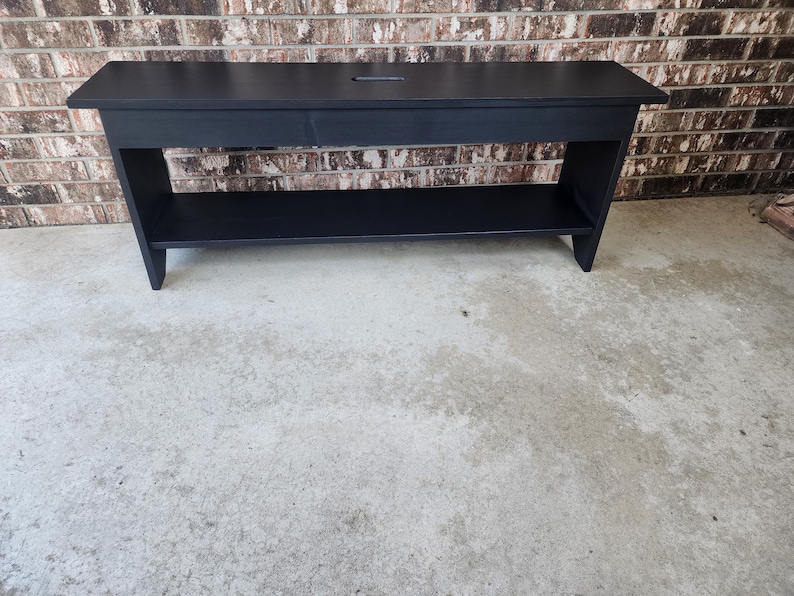 May include: A black wooden bench with a shelf underneath. The bench has a simple design and is made of solid wood.