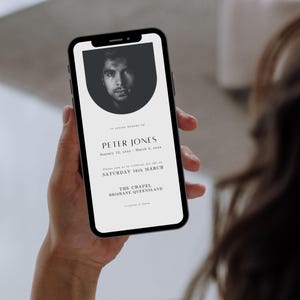 May include: A black and white photo of a man on a white mobile phone screen. The phone screen displays a funeral announcement for Peter Jones, with the date of the service on Saturday, March 16th. The announcement also includes the location of the service, The Chapel, Brisbane, Queensland.
