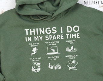 May include: Military green hoodie with the text "THINGS I DO IN MY SPARE TIME" and illustrations of scuba diving activities. The hoodie includes a hood and a front pocket.