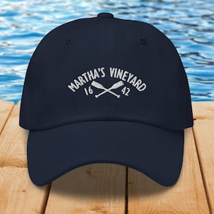 May include: A navy blue baseball cap with white embroidery that reads "Martha's Vineyard 16 42" with two crossed oars.