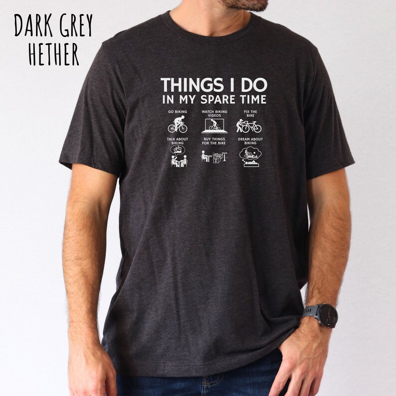 May include: A dark grey heather t-shirt with a white graphic that says "Things I do in my spare time" and lists activities related to cycling.
