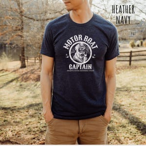 May include: A heather navy blue t-shirt with a white graphic of a sailor with a pipe and the text "Motor Boat Captain Uncharted Waters Questionable Choices".