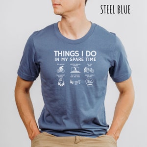 May include: A steel blue t-shirt with a white graphic that says "Things I do in my spare time" and lists activities related to cycling.