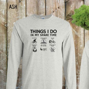 May include: A gray long-sleeve t-shirt with the text "THINGS I DO IN MY SPARE TIME" and a series of black and white illustrations depicting activities related to biking.
