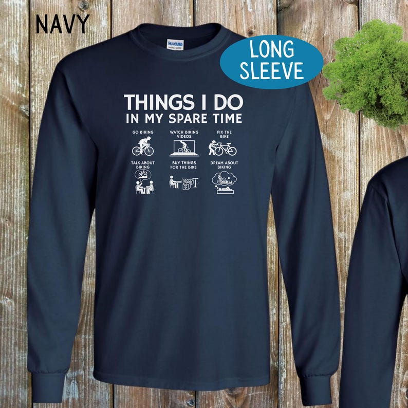 May include: Navy blue long-sleeve t-shirt with a white graphic that says "Things I do in my spare time" and includes six icons depicting activities related to cycling.