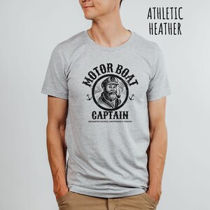 May include: A gray t-shirt with a black graphic of a captain with a pipe and the text "Motor Boat Captain Uncharted Waters, Questionable Choices".