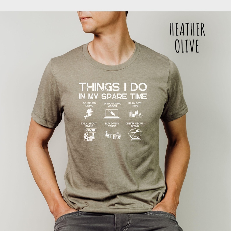 K&ouml;nnte beinhalten: Heather olivgr&uuml;nes T-Shirt mit dem Text "THINGS I DO IN MY SPARE TIME" und Illustrationen von Ger&auml;tetauchen, Videos ansehen, Reisen planen, &uuml;ber das Tauchen sprechen, Dinge kaufen und vom Tauchen tr&auml;umen.