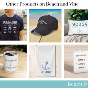 Pu&ograve; includere: Una collezione di prodotti a tema nautico. I prodotti includono una t-shirt con un elenco di cose da fare nel tempo libero, un berretto da baseball nero con la scritta "Vineyard" su di esso, un cuscino bianco con la scritta "90254 Hermosa Beach, CA" e una stella marina, una tazza da caff&egrave; bianca con un'ancora e la scritta "The Captain's Always Right...As Long As His Wife Agrees", un asciugamano da t&egrave; bianco con un'ancora blu e la scritta "Sailing", e un biglietto d'auguri con la scritta "Happy Father's Day!" e una lenza da pesca con tre pesci.
