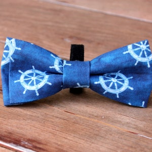 May include: A blue bow tie with a white nautical wheel pattern.