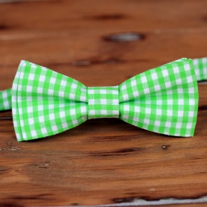 May include: A green and white gingham bow tie. The bow tie is made of a soft, lightweight fabric and has a classic, timeless design.