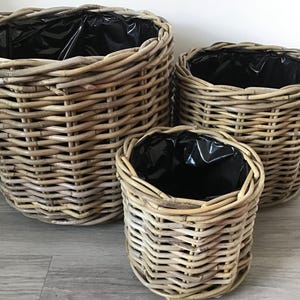 May include: Three woven wicker plant pots in different sizes. The pots are made of natural materials and have a light brown colour.