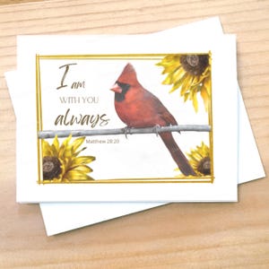 May include: A stack of white greeting cards with a gold border. The card features a watercolor image of a red cardinal perched on a branch, with sunflowers and the text "I am with you always" and "Matthew 28:20".