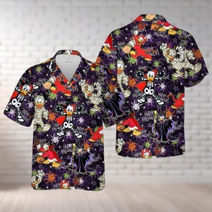 May include: Two short-sleeved button-down shirts with a Halloween-themed print. The shirts feature a dark purple background with cartoon characters, spiders, and the text "HAPPY HALLOWEEN!". The characters are dressed in Halloween costumes.