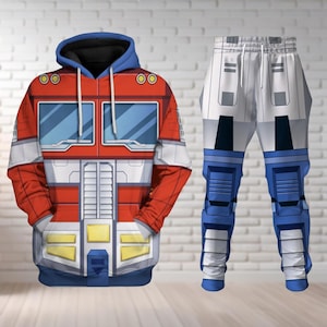 May include: A two-piece outfit comprising a red, white, blue, and yellow hoodie and matching trousers. The hoodie has a blue hood and a robot face design. The trousers are white with blue accents, mimicking the robot's leg design. The outfit is displayed against a white brick wall.