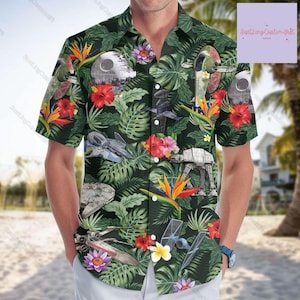 Könnte beinhalten: Ein grünes, kurzärmeliges Hemd mit Knöpfen und einem tropischen Druck mit Star Wars-Charakteren und Raumschiffen. Der Druck enthält einen Todesstern, TIE-Jäger, X-Flügel und AT-ATs.