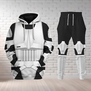 May include: A two-piece outfit featuring a white and black Stormtrooper design. The hooded sweatshirt and matching pants have a detailed graphic print resembling the iconic armor. The pants have a drawstring waist.