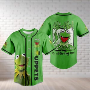 Könnte beinhalten: Grünes Baseball-Trikot mit Kermit dem Frosch und dem Text "The Muppets". Die Vorderseite des Trikots zeigt ein großes Bild von Kermit, und die Rückseite zeigt "Hi-Ho!" mit Kermit und dem Satz "Kermit the Frog here".