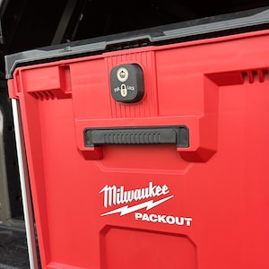 Könnte beinhalten: Eine rote Milwaukee Packout Aufbewahrungsbox mit schwarzem Griff und Verriegelungsmechanismus. Das weiße Milwaukee-Logo und der Packout-Text sind auf der Vorderseite sichtbar. Die Box hat silberne Metallstützen.