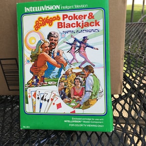 May include: A green Intellivision game cartridge for Las Vegas Poker & Blackjack by Mattel Electronics. The front of the cartridge features a colorful illustration of people playing cards in a casino setting. The text "No. 2611" is printed in the bottom left corner.