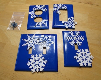 4 blue oversized outlet covers with white snowflakes.